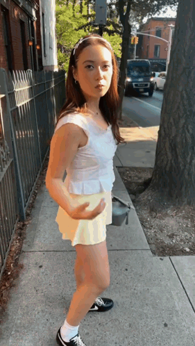Girl in White Top and Yellow Shorts on Sidewalk