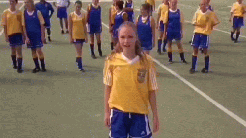 Girl in Yellow Adidas Shirt With Soccer Players