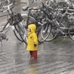Girl in Yellow Raincoat in Rain with Bikes