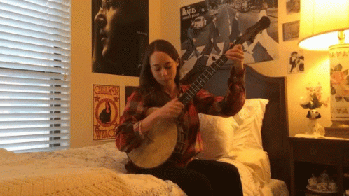 Girl Playing Banjo on Bed With Beatles Poster