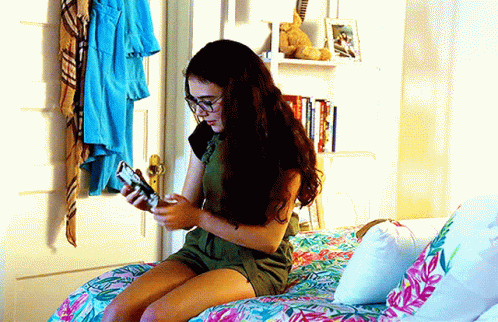 Girl Sitting on Bed Looking at Phone