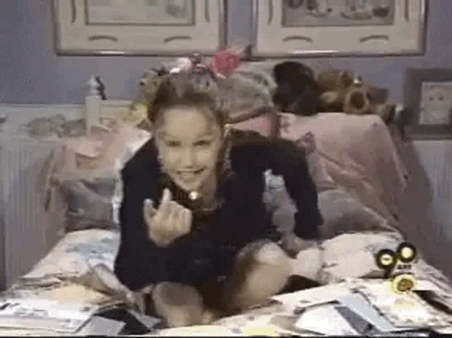 Girl Sitting On Bed With Papers GIF