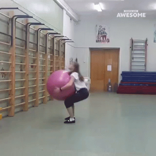 Girl Squatting With Pink Ball in Gym Saying Awesome