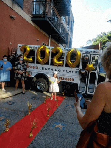 Girl Standing on Red Carpet in Front of Bus