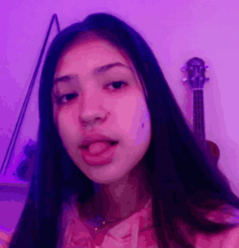 Girl Sticking Tongue Out by Purple Wall with Guitar