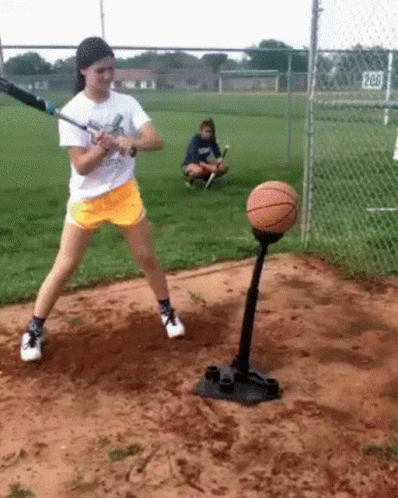 Girl Swinging Baseball Bat at Basketball on Tee
