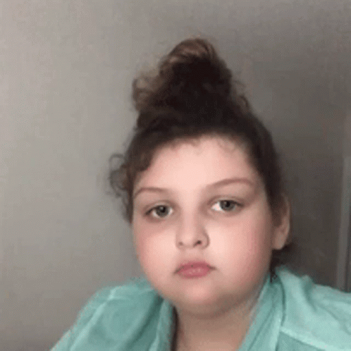 Girl with Hair Bun in Green Shirt Looking at Camera