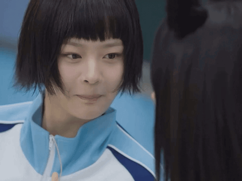 Girl with Short Black Hair and Blue Jacket Looks at Another Girl