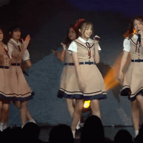 Girls in School Uniforms Singing Into Microphones