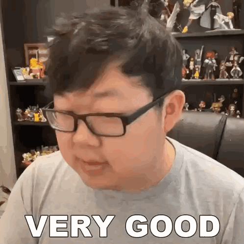 Glasses Man Says Very Good With Figurine Shelf GIF