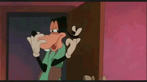 Goofy From Mickey Mouse Is Standing In Front Of A Door And Talking On A Cell Phone . GIF