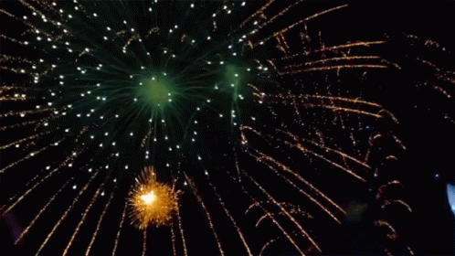 Green And Gold Fireworks In The Night Sky With A Boat In The Background GIF