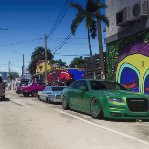 Green Car Parked in Front of Building With Graffiti