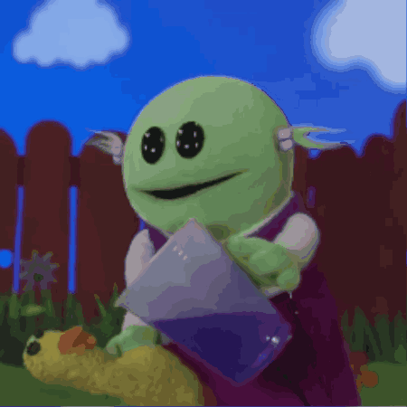 Green Cartoon Character Holding Purple Bag by Fence