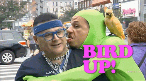 Green Costumed Man Hugging Man With Parrot And Bird GIF