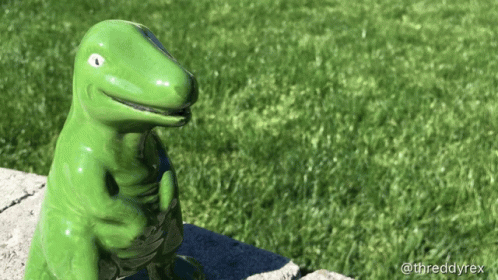 Green Dinosaur Statue Sitting on Sidewalk