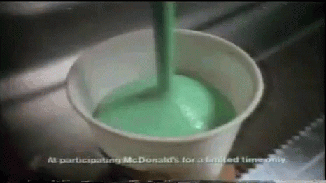 Green Liquid Is Being Poured Into A Cup From A Spoon . GIF