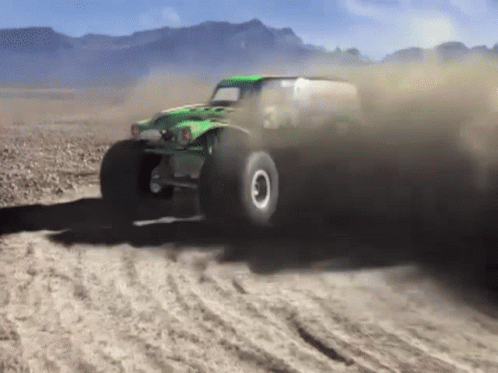 Green Monster Truck Driving on Dirt Road with Mountains