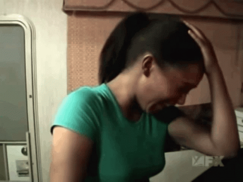 Green Shirt Woman Holding Head Near FX Logo