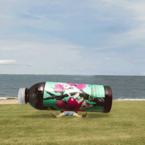 Green Tea Bottle Floating Above Beach GIF