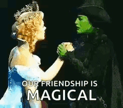 Green Woman in Top Hat and Blue Dress Woman Holding Hands