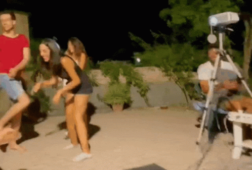 Group Dancing In Front Of Projector While Man Sits In Chair GIF