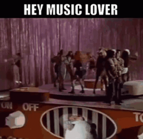Group Dancing on Stage With Hey Music Lover Sign