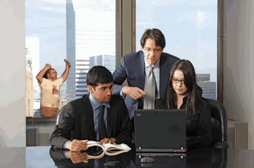 Group Looking at Laptop With Man in T-Shirt Behind
