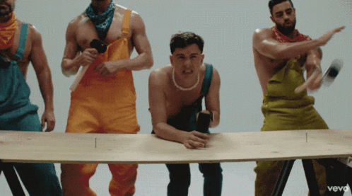 Group of Men in Colorful Overalls Around Table With Vevo