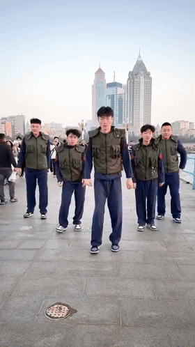 Group Of Men On Sidewalk In Front Of City GIF