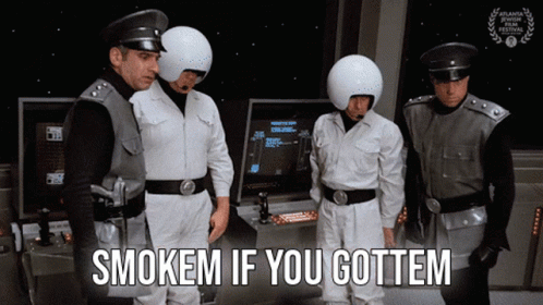 Group of Men Standing in Front of Arcade Machine Saying Smokem If You Gottem