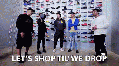 Group of Men Standing in Front of Wall Filled With Sneakers