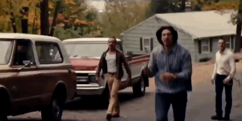 Group Of Men Walking On Street Near House GIF