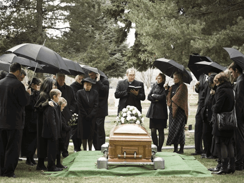 Group Of People Around Coffin In Cemetery Under Umbrellas GIF