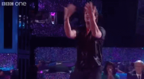 Group Of People Dancing On Stage In Front Of BBC One Sign GIF