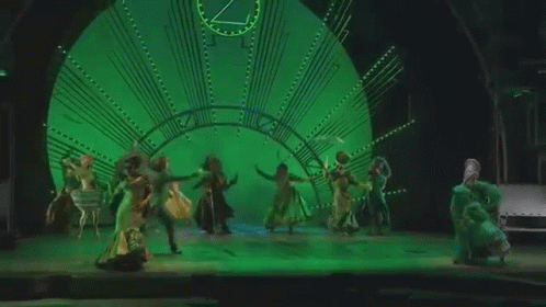 Group Of People Dancing On Stage In Front Of Clock GIF
