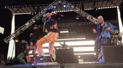 Group Of People Dancing On Stage In Front Of Large Light GIF