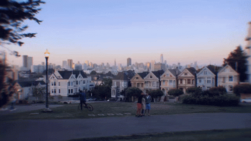 Group Of People In Front Of Row Of Houses With City Skyline GIF