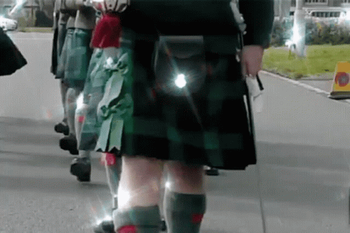 Group of People in Kilts Walking Down Street