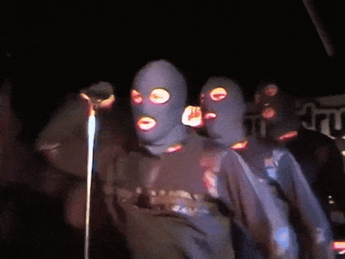 Group of People in Ski Masks at Microphone