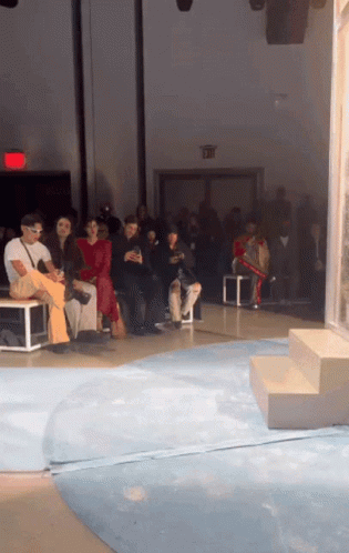 Group of People Sitting in Room With Red Exit Sign