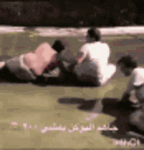 Group of People Sitting on Grass With Arabic Writing