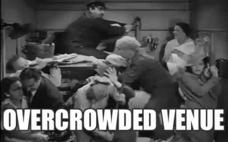 Group of People Standing Around Table Overcrowded Venue