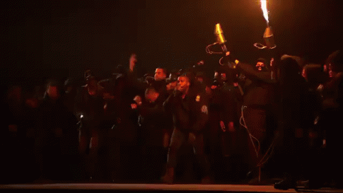 Group Of People Standing On Stage With Large Fire GIF