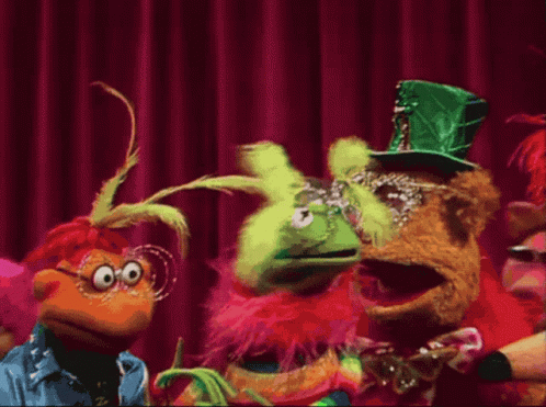 Group of Stuffed Animals on Stage With Red Curtain