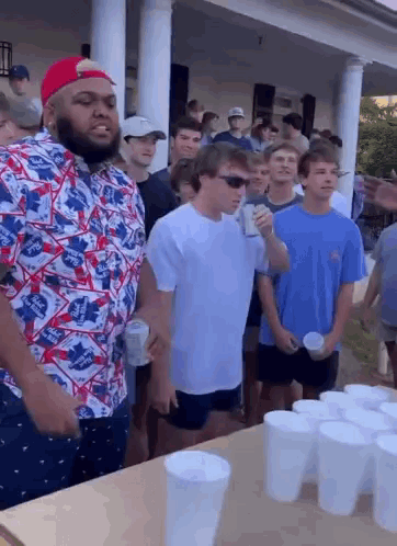 Group of Young Men Standing Around Table With Cups