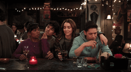 Group Sitting at Bar With Please Sign