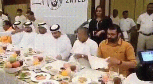 Group Sitting at Table with Food and United Sign