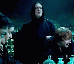 Group Sitting at Table With Man in Black Cape and Bottles