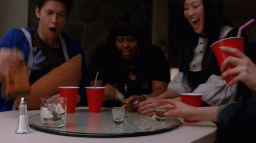 Group Sitting at Table With Shot Glasses and Red Cups